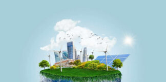 Hand holding small earth model with city and greenery.