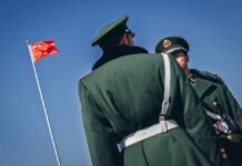 TRAPPED: Year-Long Waits Behind Bars Without Treatment Two Chinese soldiers in uniform standing near the national flag