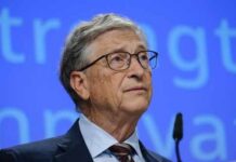 A man in a suit speaking at a conference with a blue background