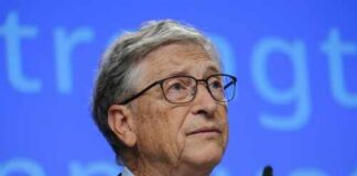 A man in a suit speaking at a conference with a blue background
