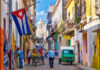 Colorful street scene with Cuban flag and people.