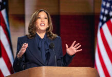 Person speaking at podium with American flags behind
