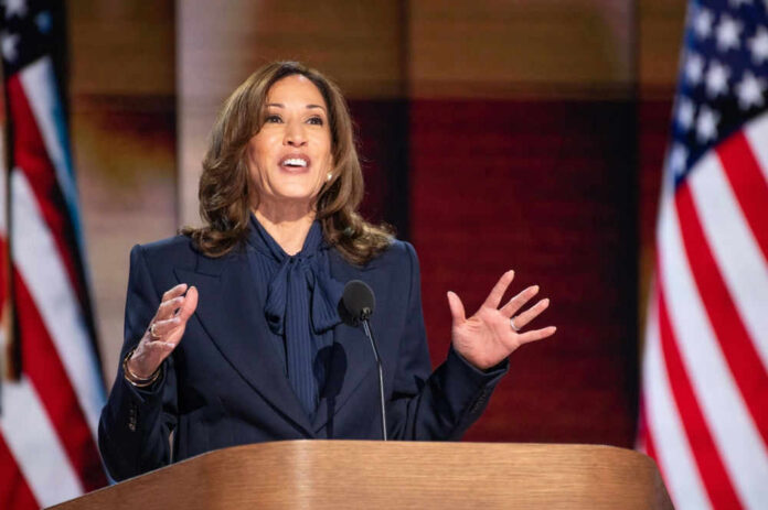 Person speaking at podium with American flags behind