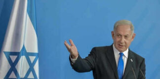 Man speaking next to Israeli flag.