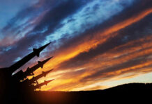 Silhouette of missiles against dramatic sunset sky.