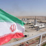 Middle East Conflict Drains Global Economies Iranian flag waving in front of an oil processing facility