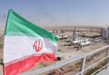 Iranian flag waving in front of an oil processing facility