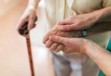 Two hands clasped together, one elderly and one younger, symbolizing support