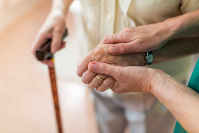 Two hands clasped together, one elderly and one younger, symbolizing support