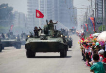 Military tanks parading down a street with a cheering crowd