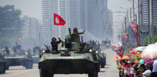 Military tanks parading down a street with a cheering crowd