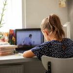 A child sitting at a desk with a laptop and books, focused on learning