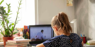 A child sitting at a desk with a laptop and books, focused on learning