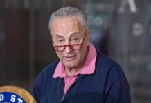 A man with glasses speaking at a press conference