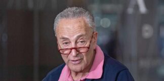 A man with glasses speaking at a press conference
