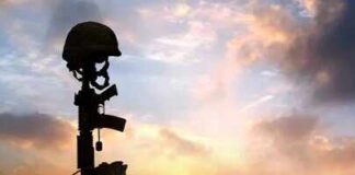 Silhouette of a soldier's helmet and rifle against a sunset