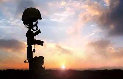 Silhouette of a soldier's helmet and rifle against a sunset