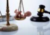 Scales of justice with a small baby figurine on one side and a gavel in the background