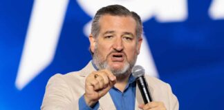 A man in a light suit speaking passionately into a microphone