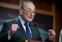 Trump SLAMS Schumer: DHS Shutdown Madness A politician delivering a passionate speech at a podium
