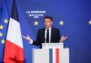 Emmanuel Macron delivering a speech at La Sorbonne with flags in the background