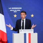Allied Tensions BOIL Over Secret Strikes – UN Scramble Emmanuel Macron delivering a speech at La Sorbonne with flags in the background