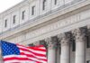 Facade of a United States courthouse with an American flag in the foreground
