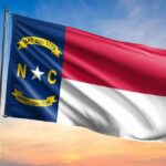 North Carolina state flag waving against a sunset sky