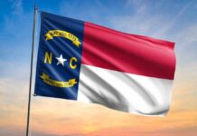 North Carolina state flag waving against a sunset sky
