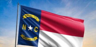 North Carolina state flag waving against a sunset sky