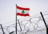 Lebanese flag waving next to barbed wire fence