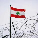 Lebanese flag waving next to barbed wire fence