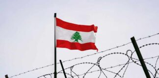 Lebanese flag waving next to barbed wire fence