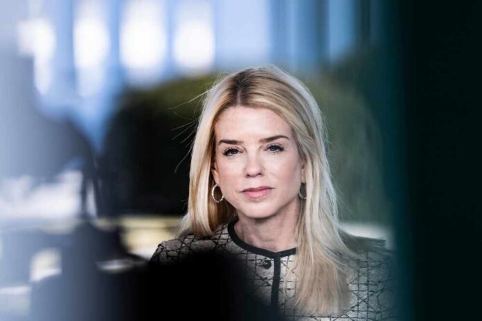 A professional woman with long blonde hair and a serious expression, wearing business attire