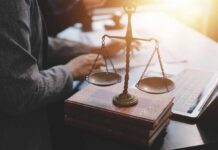 A set of legal scales on top of law books with a person working in the background