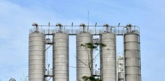 Metal storage silos at an industrial facility against a blue sky