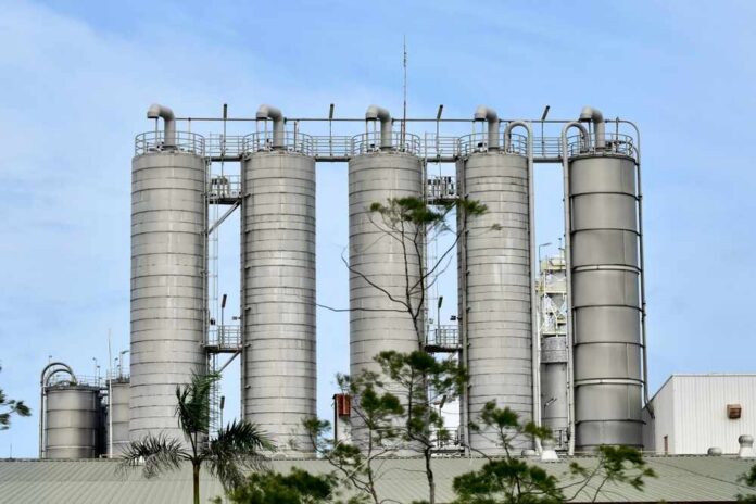 Metal storage silos at an industrial facility against a blue sky