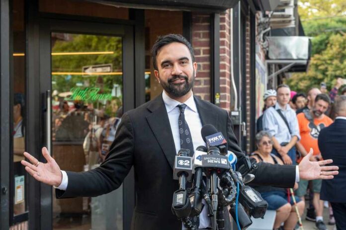 Man in a suit speaking at a press conference with microphones in front of him