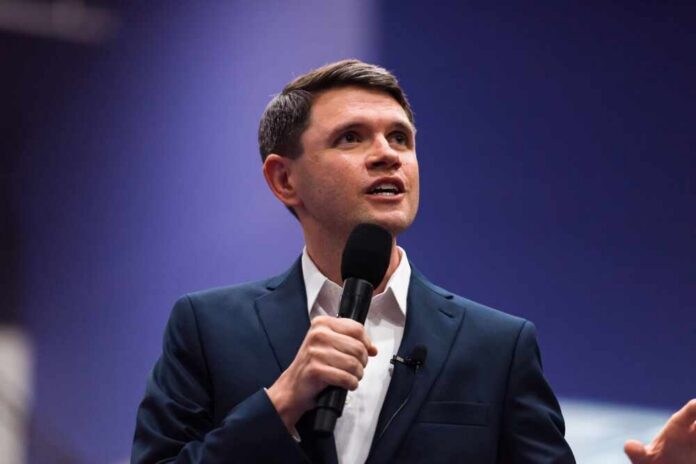 A man in a suit speaking into a microphone during a presentation