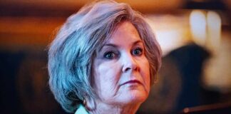 A mature woman with a serious expression in an indoor setting