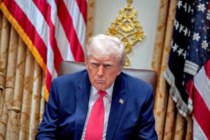 Donald Trump seated in the Oval Office with a serious expression