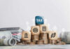 Wooden blocks on stacked coins with tax symbols