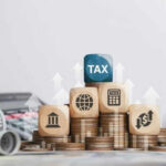 Wooden blocks on stacked coins with tax symbols