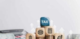 Wooden blocks on stacked coins with tax symbols