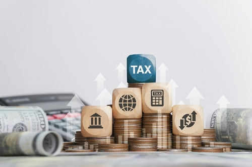 Wooden blocks on stacked coins with tax symbols