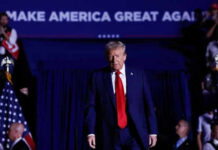 Man in suit walking on stage with audience background