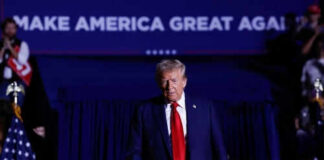 Man in suit walking on stage with audience background