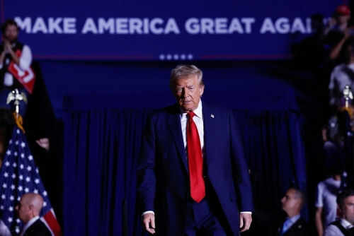 Man in suit walking on stage with audience background