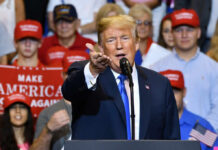 Man speaking at rally with crowd behind him