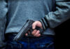 Person holding a handgun behind their back
